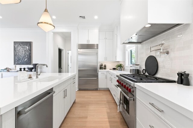 50 Depot Rd, Westhampton Beach, NY 11978 - kitchen featuring high quality appliances, a sink, wall chimney range hood, light countertops, and white cabinets