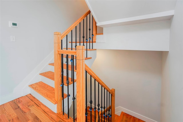 staircase featuring wood finished floors and baseboards