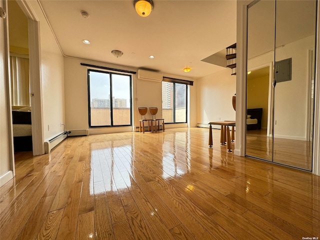 empty room with a wall mounted air conditioner, light wood-type flooring, baseboards, baseboard heating, and electric panel