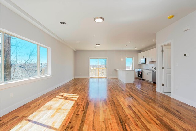 unfurnished living room with light wood-style flooring, baseboards, and recessed lighting