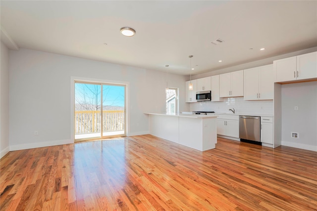kitchen with stainless steel appliances, light wood finished floors, white cabinetry, and recessed lighting