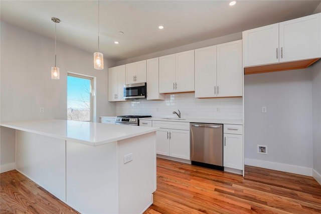 kitchen with stainless steel appliances, a sink, backsplash, light wood-style floors, and light countertops