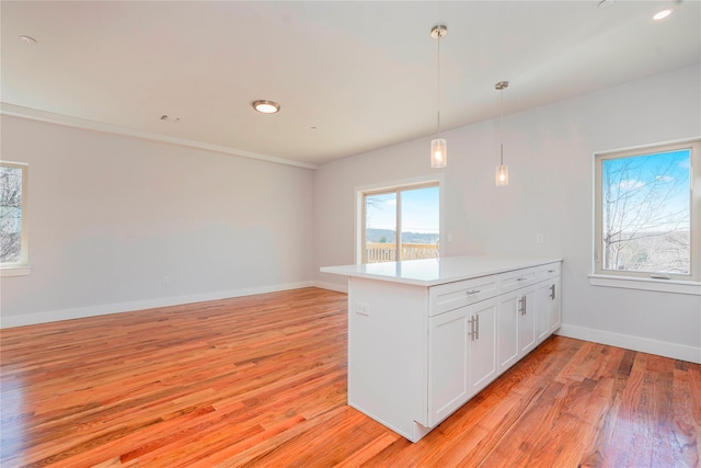 kitchen featuring a peninsula, light wood-style flooring, white cabinetry, and light countertops