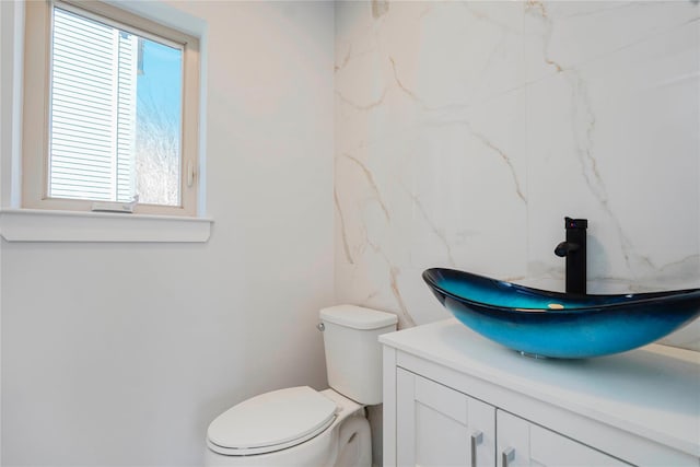 half bath featuring vanity, toilet, and tile walls