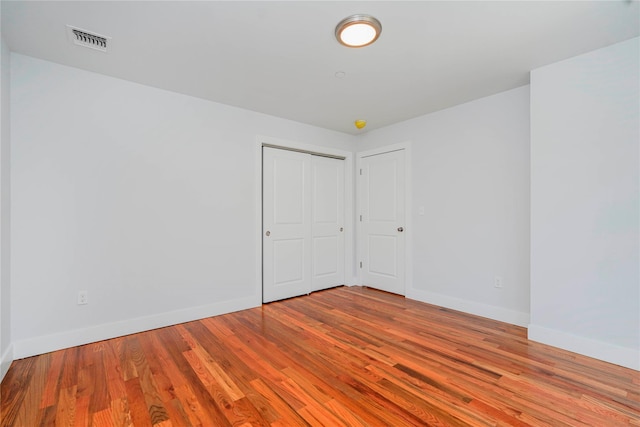 unfurnished bedroom featuring baseboards, wood finished floors, and a closet