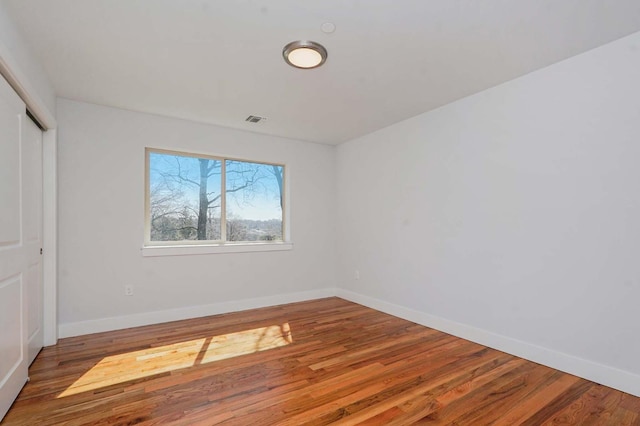 unfurnished bedroom with wood finished floors, a closet, and baseboards