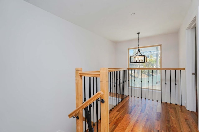 hallway featuring an upstairs landing, a chandelier, and wood finished floors