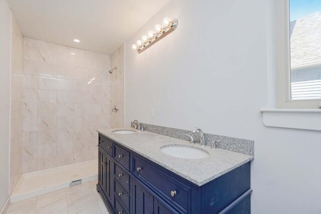 full bath featuring a tile shower, healthy amount of natural light, and double vanity