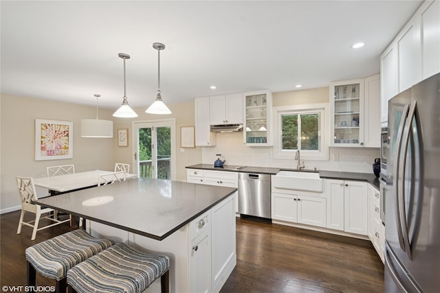 475 Lilac Ln, Cutchogue, NY 11935 - kitchen featuring appliances with stainless steel finishes, dark countertops, decorative backsplash, a kitchen breakfast bar, and under cabinet range hood