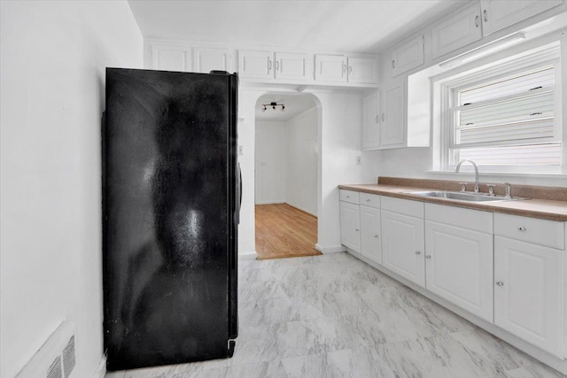 1230 Arnow Ave, Bronx, NY 10469 - kitchen featuring freestanding refrigerator, a sink, arched walkways, and white cabinets