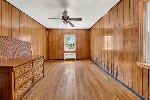 1230 Arnow Ave, Bronx, NY 10469 - empty room with radiator heating unit, light wood-type flooring, a ceiling fan, and wood walls