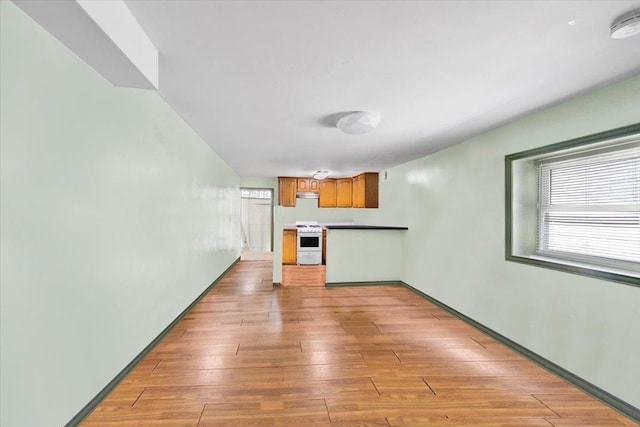1230 Arnow Ave, Bronx, NY 10469 - kitchen featuring white range, light wood-style flooring, brown cabinetry, and a peninsula