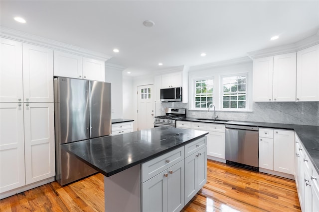 381 Wading River Rd, Manorville, NY 11949 - kitchen featuring appliances with stainless steel finishes, a sink, light wood-type flooring, white cabinets, and crown molding