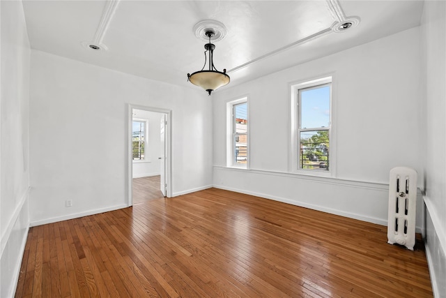 unfurnished room featuring radiator heating unit, hardwood / wood-style flooring, and baseboards