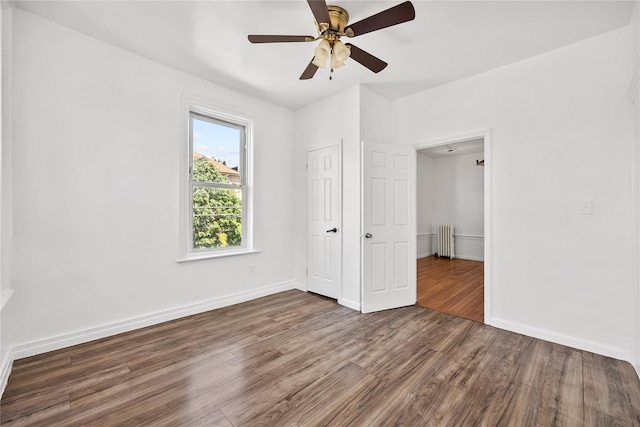 unfurnished bedroom featuring radiator heating unit, wood finished floors, baseboards, and ceiling fan