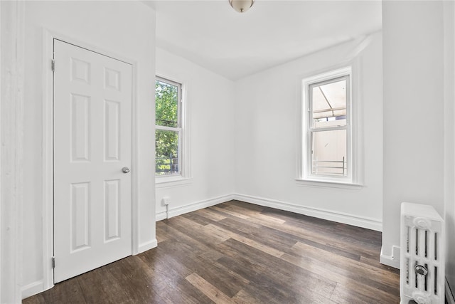 unfurnished bedroom featuring radiator heating unit, dark wood-style floors, and baseboards