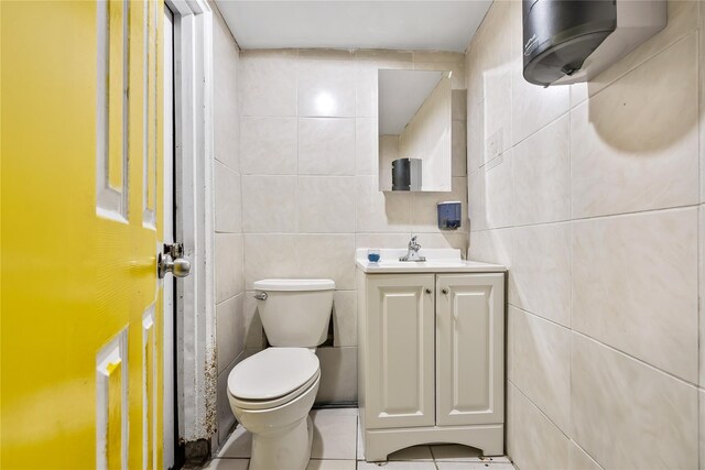 half bath featuring tile walls, toilet, vanity, and tile patterned floors