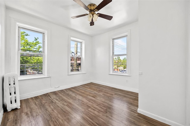 unfurnished room featuring dark wood finished floors, a ceiling fan, and baseboards