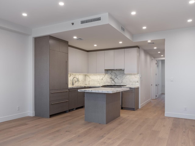 kitchen with light countertops, backsplash, a center island, baseboards, and modern cabinets