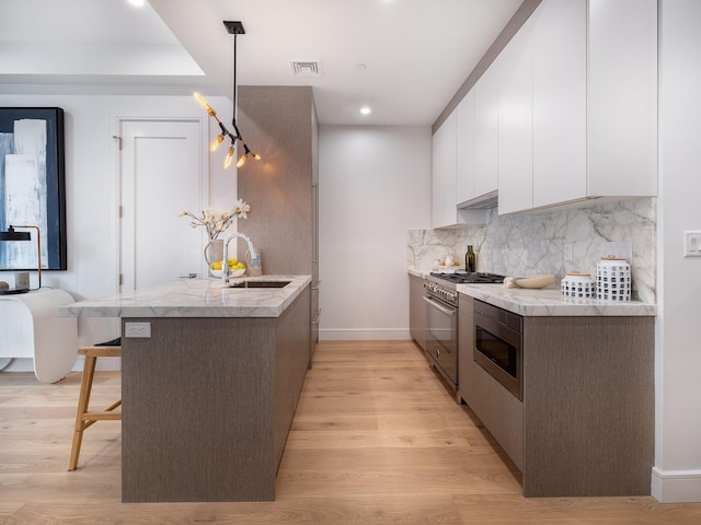 kitchen featuring a sink, stainless steel appliances, white cabinetry, modern cabinets, and tasteful backsplash