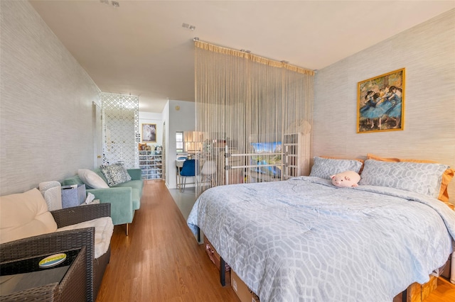 bedroom with wood finished floors and wallpapered walls