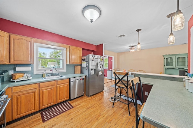 149 E Main St, Washingtonville, NY 10992 - kitchen featuring appliances with stainless steel finishes, a sink, pendant lighting, light wood-style flooring, and brown cabinetry