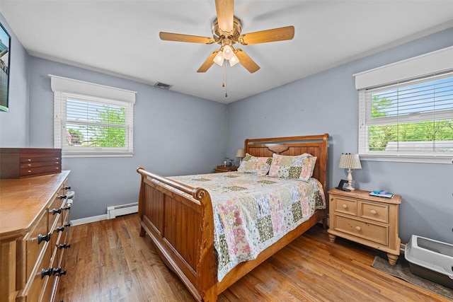 149 E Main St, Washingtonville, NY 10992 - bedroom with a baseboard heating unit, multiple windows, wood finished floors, and a ceiling fan