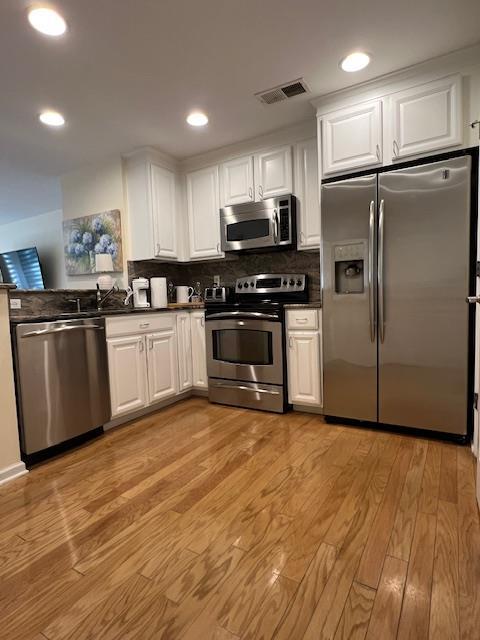 1105 Round Pointe Dr, Haverstraw, NY 10927 - kitchen with stainless steel appliances, dark countertops, light wood-type flooring, white cabinetry, and recessed lighting