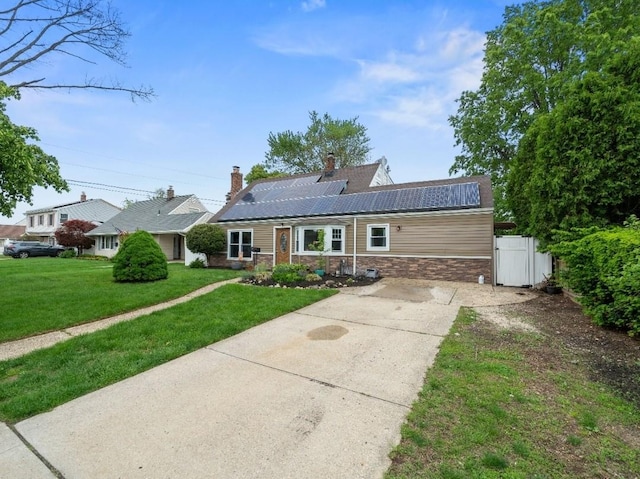 33 Saddle Ln, Levittown, NY 11756 - view of front of property with concrete driveway, roof mounted solar panels, a chimney, and stone siding