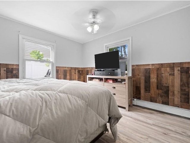 33 Saddle Ln, Levittown, NY 11756 - bedroom featuring multiple windows, light wood-style flooring, a wainscoted wall, ceiling fan, and baseboard heating