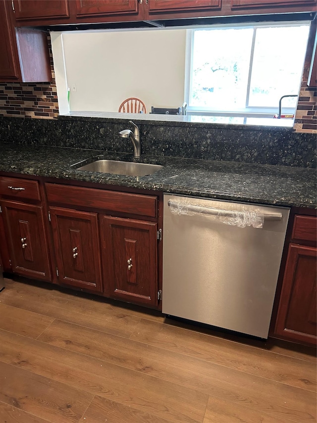 kitchen with stainless steel dishwasher, a sink, decorative backsplash, and light wood-type flooring