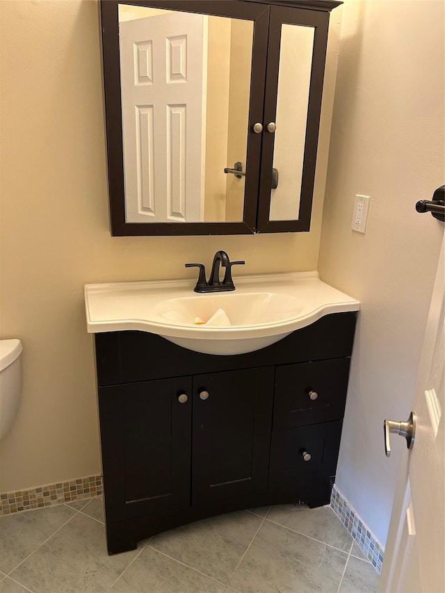 bathroom with vanity, baseboards, toilet, and tile patterned floors