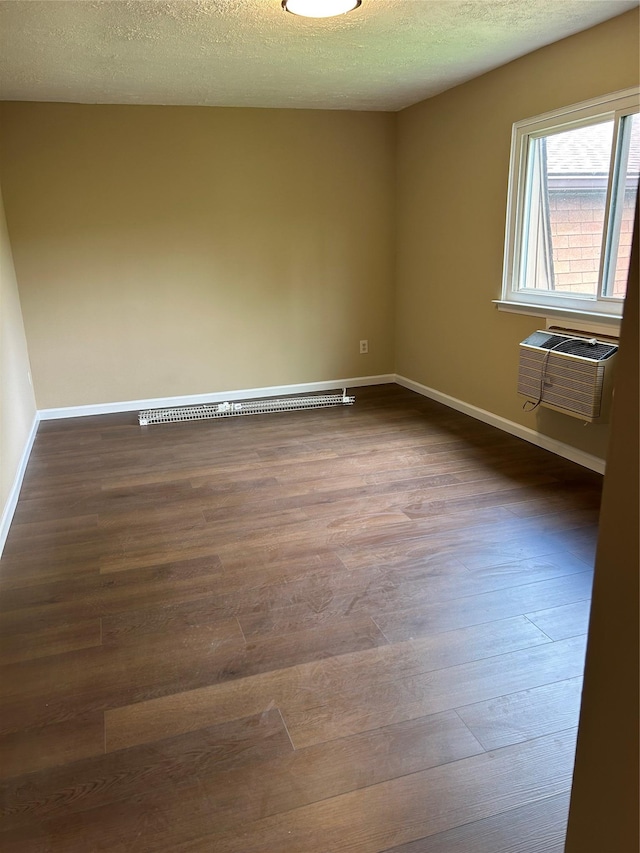 unfurnished room with a wall mounted air conditioner, dark wood-type flooring, baseboards, and a textured ceiling