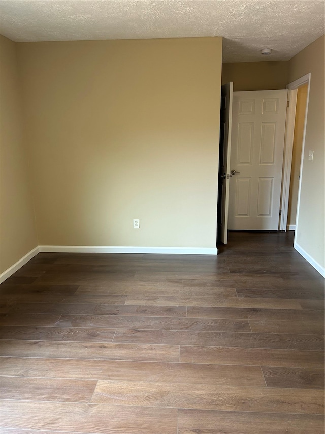 empty room with dark wood-type flooring, baseboards, a textured ceiling, and a smoke detector