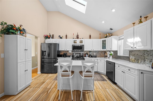178 Prospect Pl, Bay Shore, NY 11706 - kitchen featuring appliances with stainless steel finishes, a skylight, high vaulted ceiling, tasteful backsplash, and white cabinets