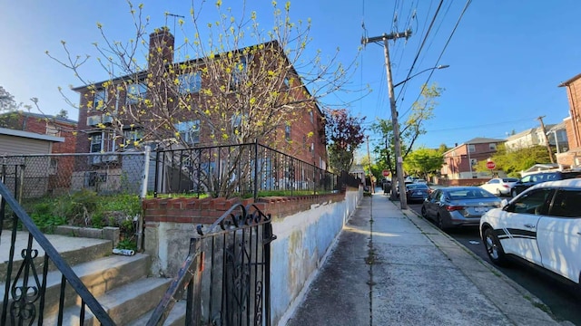 view of asphalt road featuring sidewalks, street lights, traffic signs, and a residential view