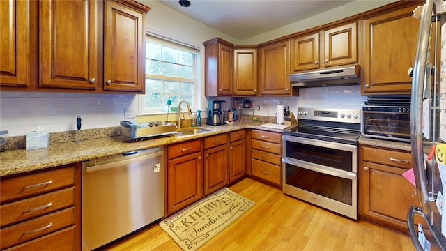 10 Courtney Ln, Brewster, NY 10509 - kitchen featuring appliances with stainless steel finishes, under cabinet range hood, decorative backsplash, light wood-style floors, and brown cabinetry