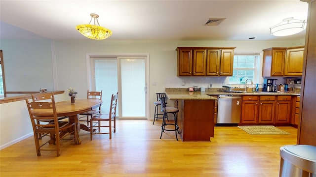 10 Courtney Ln, Brewster, NY 10509 - kitchen with stainless steel dishwasher, light wood-type flooring, a kitchen breakfast bar, and brown cabinetry