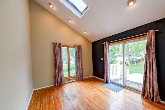 doorway to outside featuring a skylight, light wood-style floors, baseboards, high vaulted ceiling, and recessed lighting