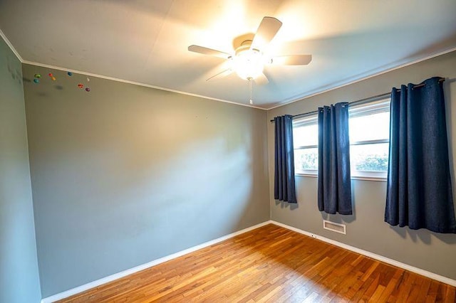 unfurnished room featuring wood finished floors, baseboards, a ceiling fan, and ornamental molding