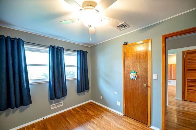 unfurnished bedroom featuring wood finished floors, baseboards, crown molding, and ceiling fan