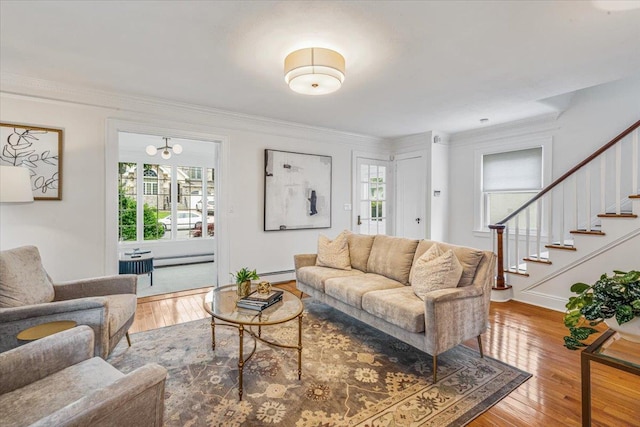 living room featuring healthy amount of natural light, a baseboard heating unit, hardwood / wood-style flooring, and ornamental molding