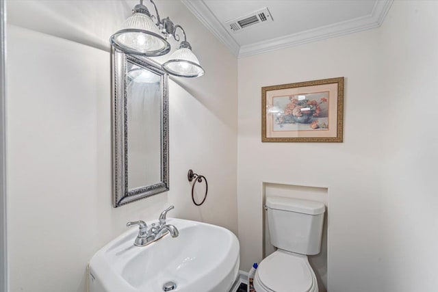 half bathroom with a sink, toilet, and ornamental molding