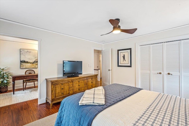 bedroom featuring wood finished floors, a closet, ornamental molding, ceiling fan, and baseboards