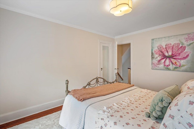 bedroom featuring wood finished floors, ornamental molding, and baseboards