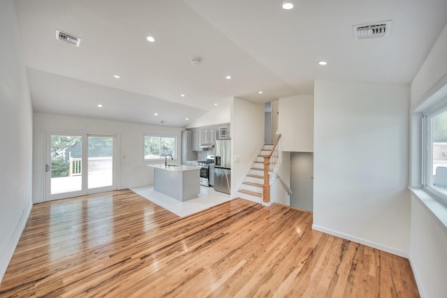 48 Hillside Ave, Patchogue, NY 11772 - unfurnished living room featuring a sink, lofted ceiling, light wood-style floors, stairs, and recessed lighting