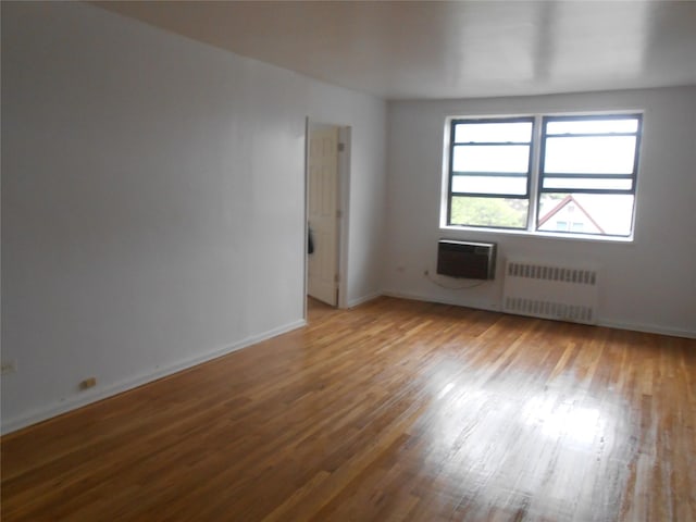 131-11KEWGARDENS Kew Gardens Rd Unit 4D, Richmond Hill, NY 11418 - spare room featuring radiator heating unit, wood finished floors, an AC wall unit, and baseboards