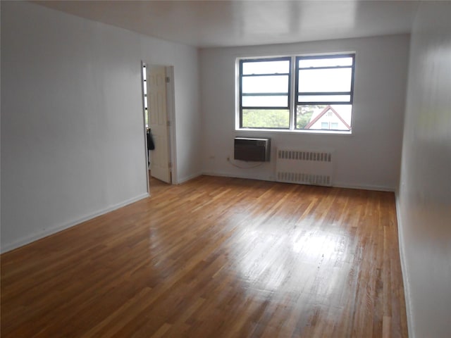131-11KEWGARDENS Kew Gardens Rd Unit 4D, Richmond Hill, NY 11418 - unfurnished room featuring radiator, an AC wall unit, wood finished floors, and baseboards