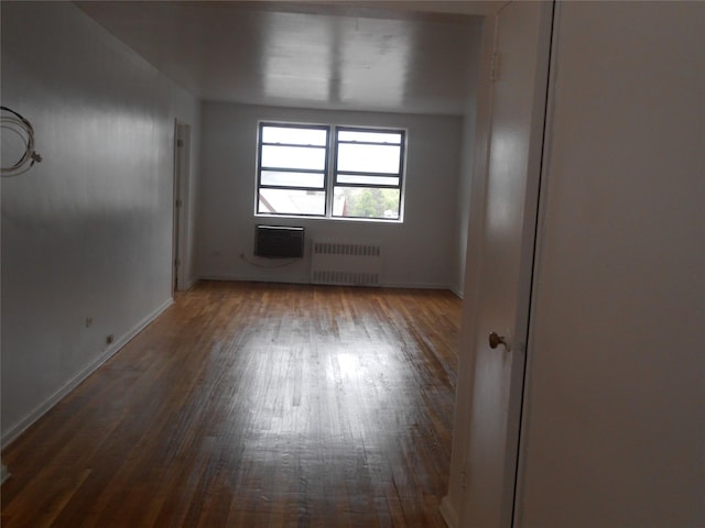 131-11KEWGARDENS Kew Gardens Rd Unit 4D, Richmond Hill, NY 11418 - spare room with radiator heating unit, wood finished floors, baseboards, and an AC wall unit