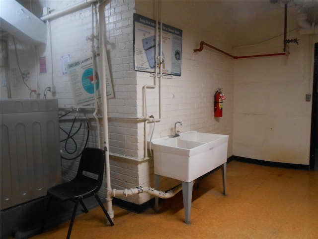 131-11KEWGARDENS Kew Gardens Rd Unit 4D, Richmond Hill, NY 11418 - basement with light flooring, brick wall, and a sink